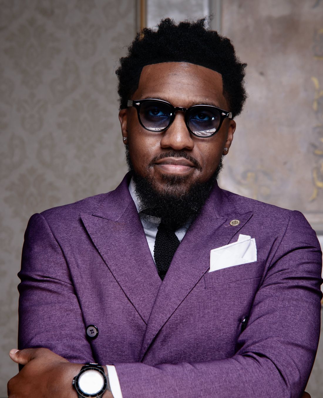 Jahleel Spence in a purple double-breasted suit, arms crossed