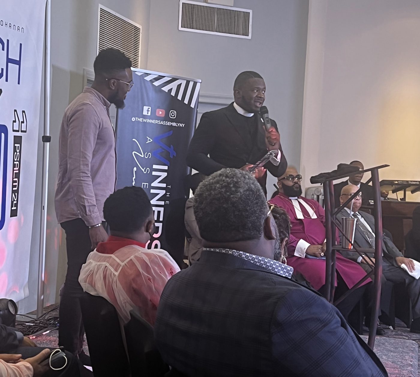 Pastor Vincent Bohanan holding an award as he honors Jahleel Spence, standing beside him, at The Winners' Assembly